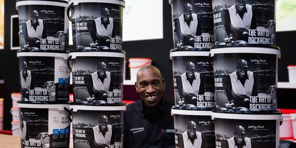 Larry Hunt with buckets of plastic buckets and his image on them.