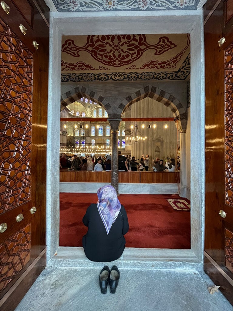 A lady watches visitors at the Blue Mosque