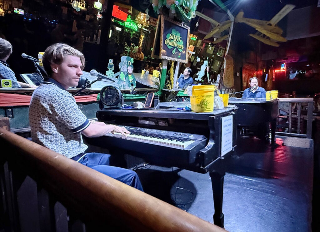 Guy playing a grand piano dueling across the stage with a friend at Silky O'Sullivans on Beale Street