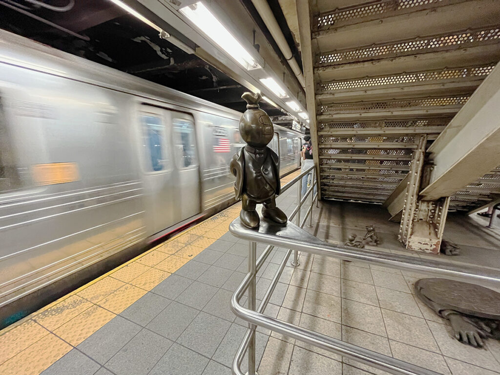 Subway sculptures at 14th Street station New York with train coming into the station
