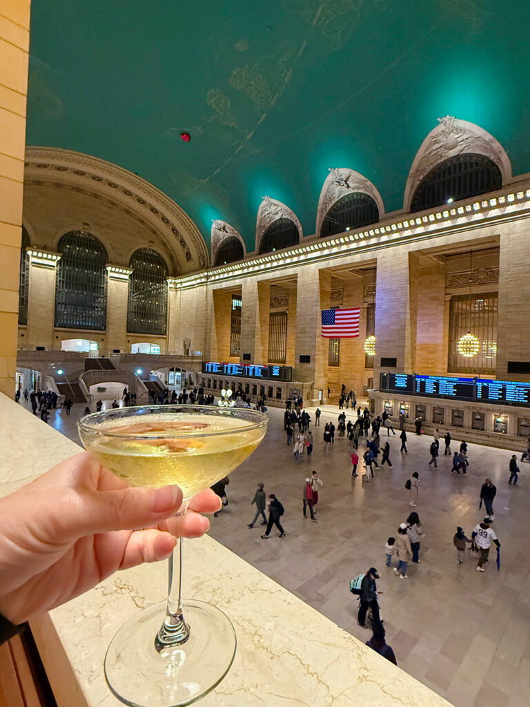 Megan holding glass of champagne in Grand Central Station