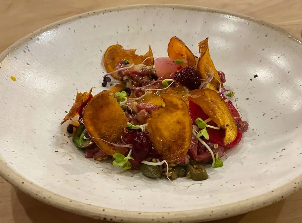 Raw steak tartare starter with kumara chips and an egg yolk