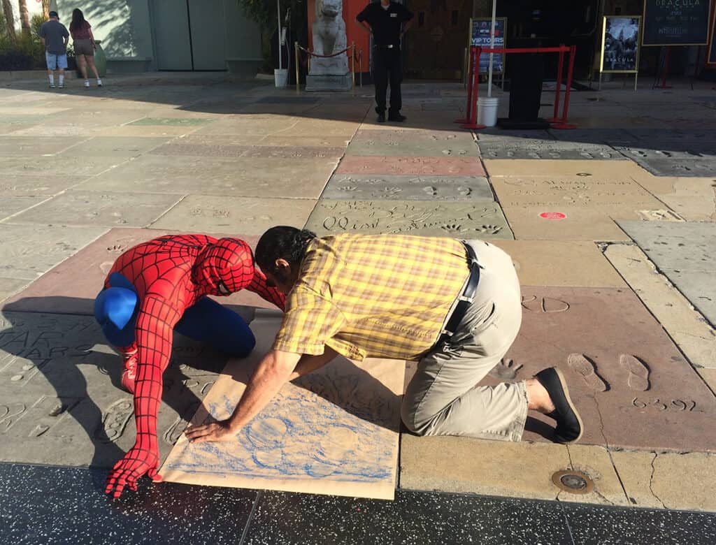 Spiderman helping a visitor with a footprint rubbing at Hollywood Walk of Fame