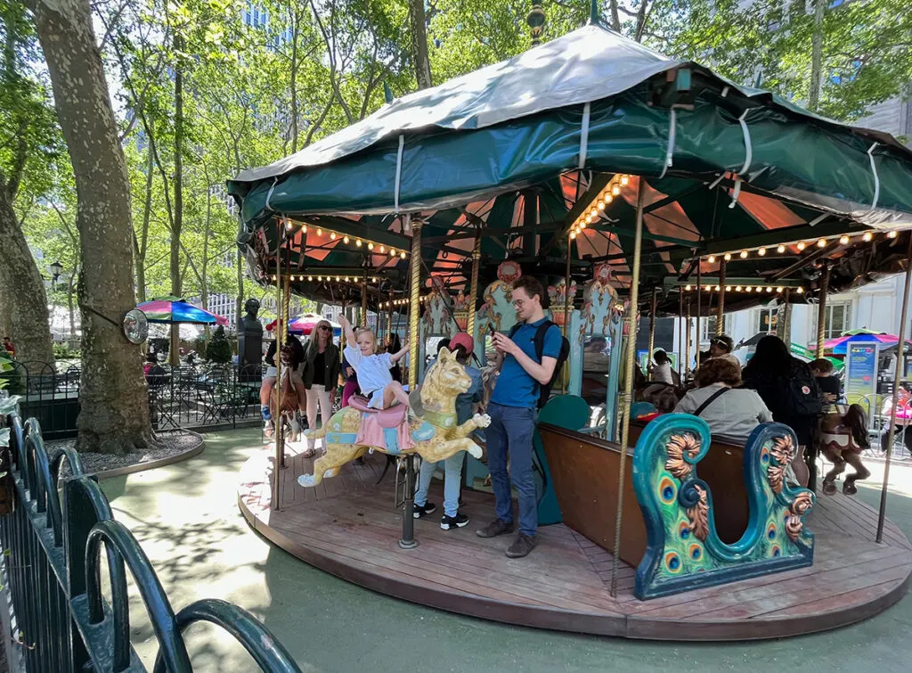 Cute girl waving to me from the carousel at Bryant Park in the summer!