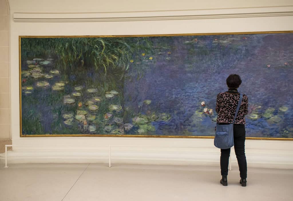 A visitor looks at waterlilies at Musée de l'Orangerie
