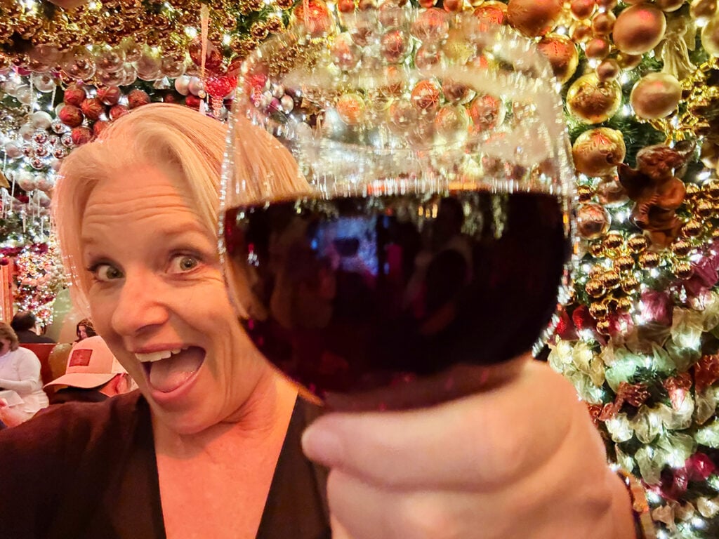 Megan having a glass of mulled wine at Rolf's with Christmas baubles all around