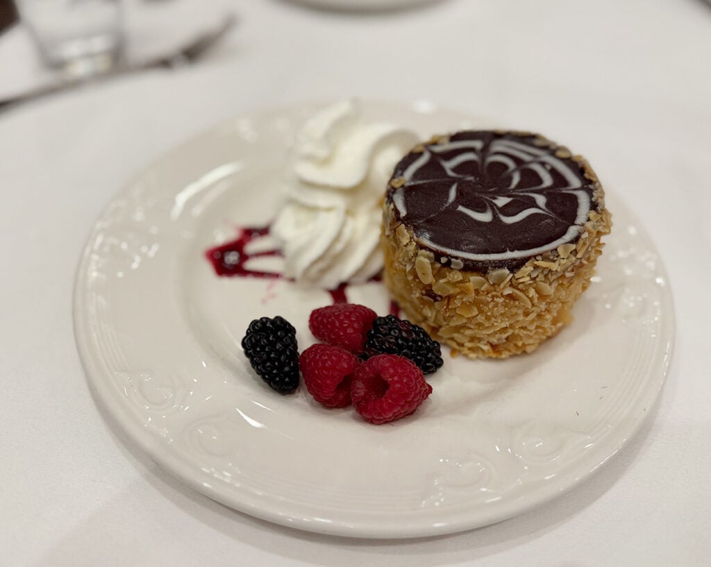 A little Boston cream pie on a plate with berry garnish