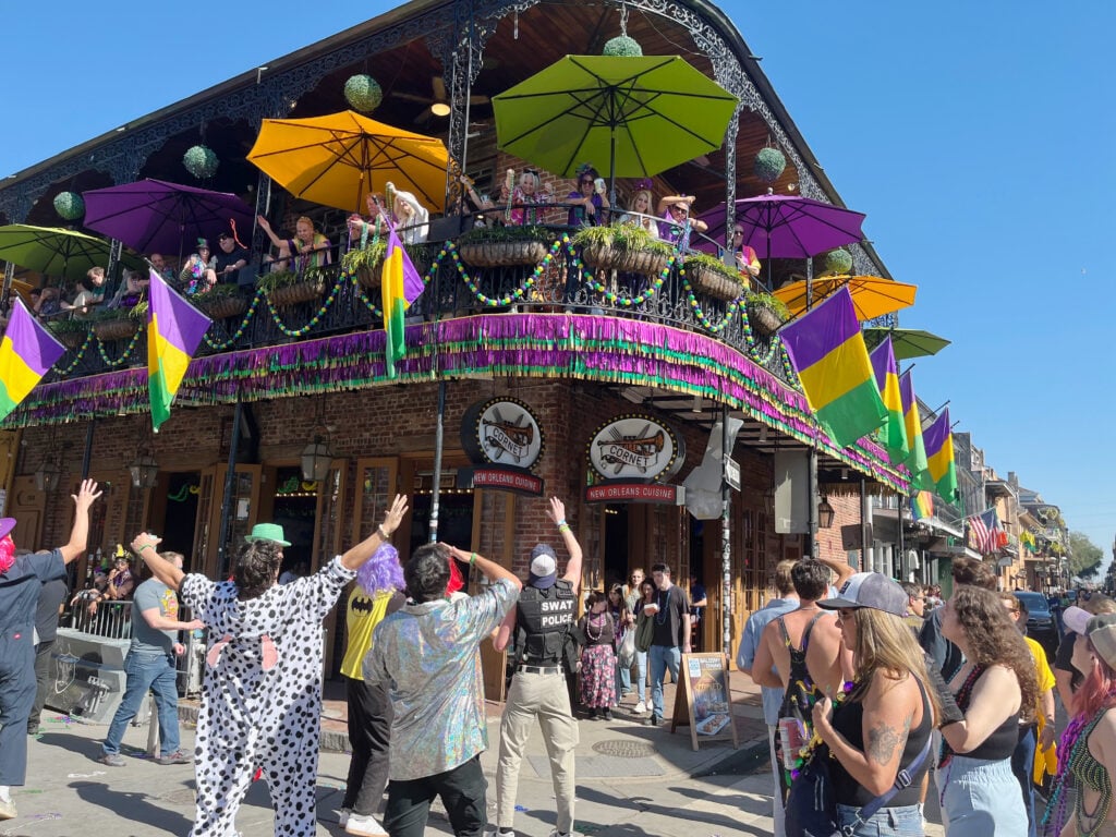 Megan throwing mardi gras beads from balcony party on Bourbon Street