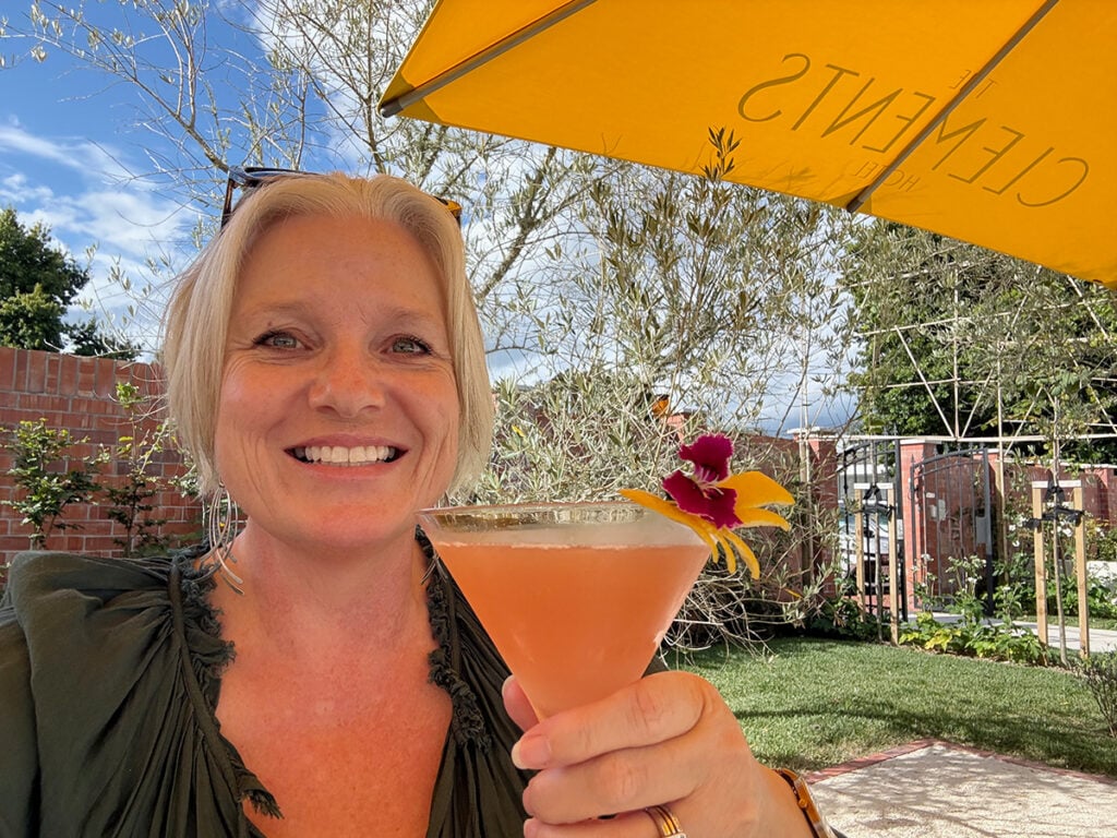 Megan with Cosmopolitan cocktail under sun umbrella at Clements Hotel