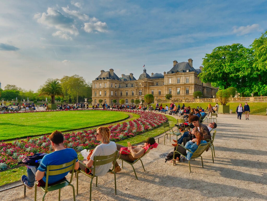 People sitting in chairs scattered around the Luxembourg Gardens