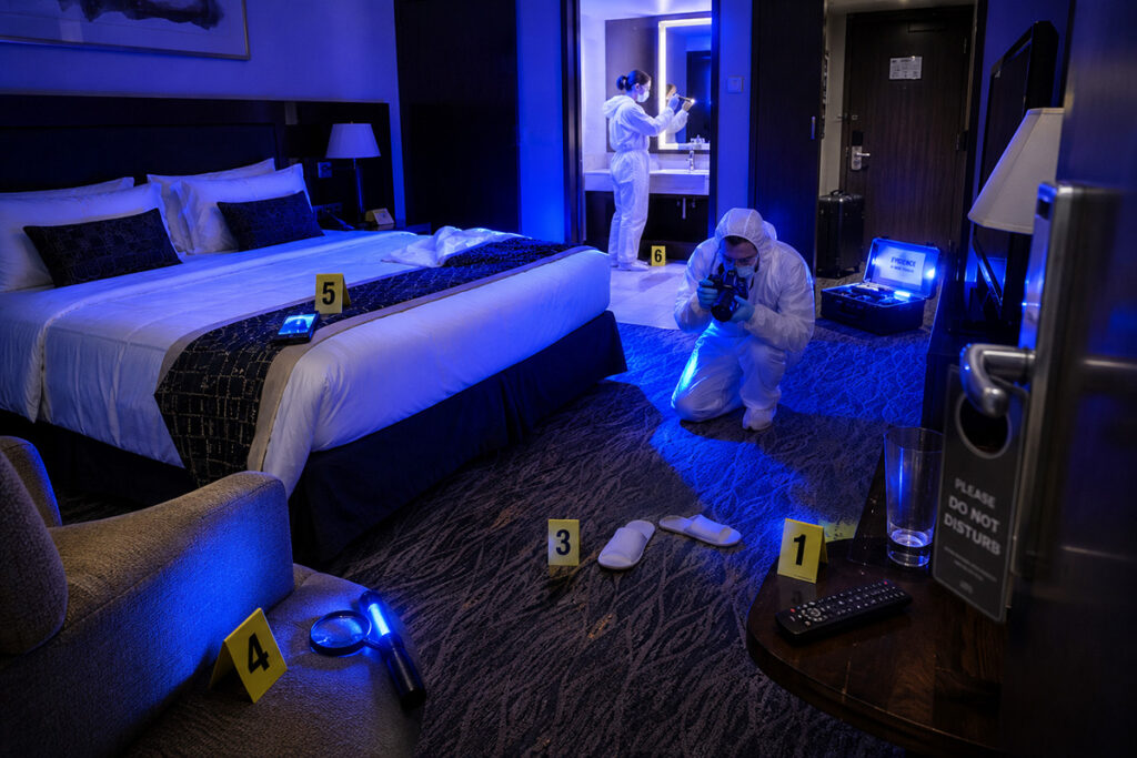 CSI agents studying a hotel room under blue light