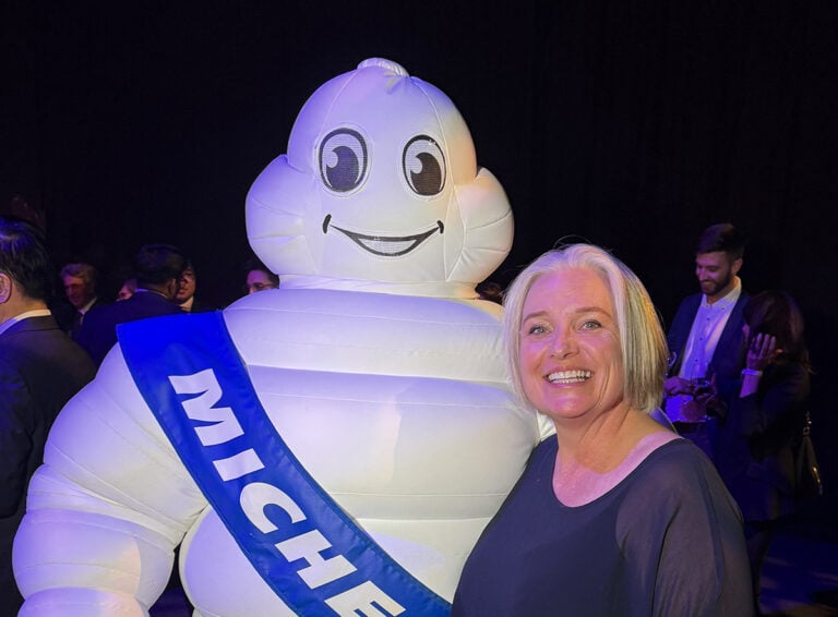 Megan smiles brightly next to the Michelin Man at The Michelin Guide launch event in New Zealand.