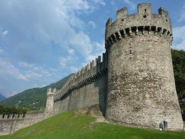 A huge tower of the Castle Grande with its walls extending around the castle and a green grass below.