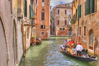 A gondola with tourists discovering Venice while navigating in one of its waterways in the Grand Canal.